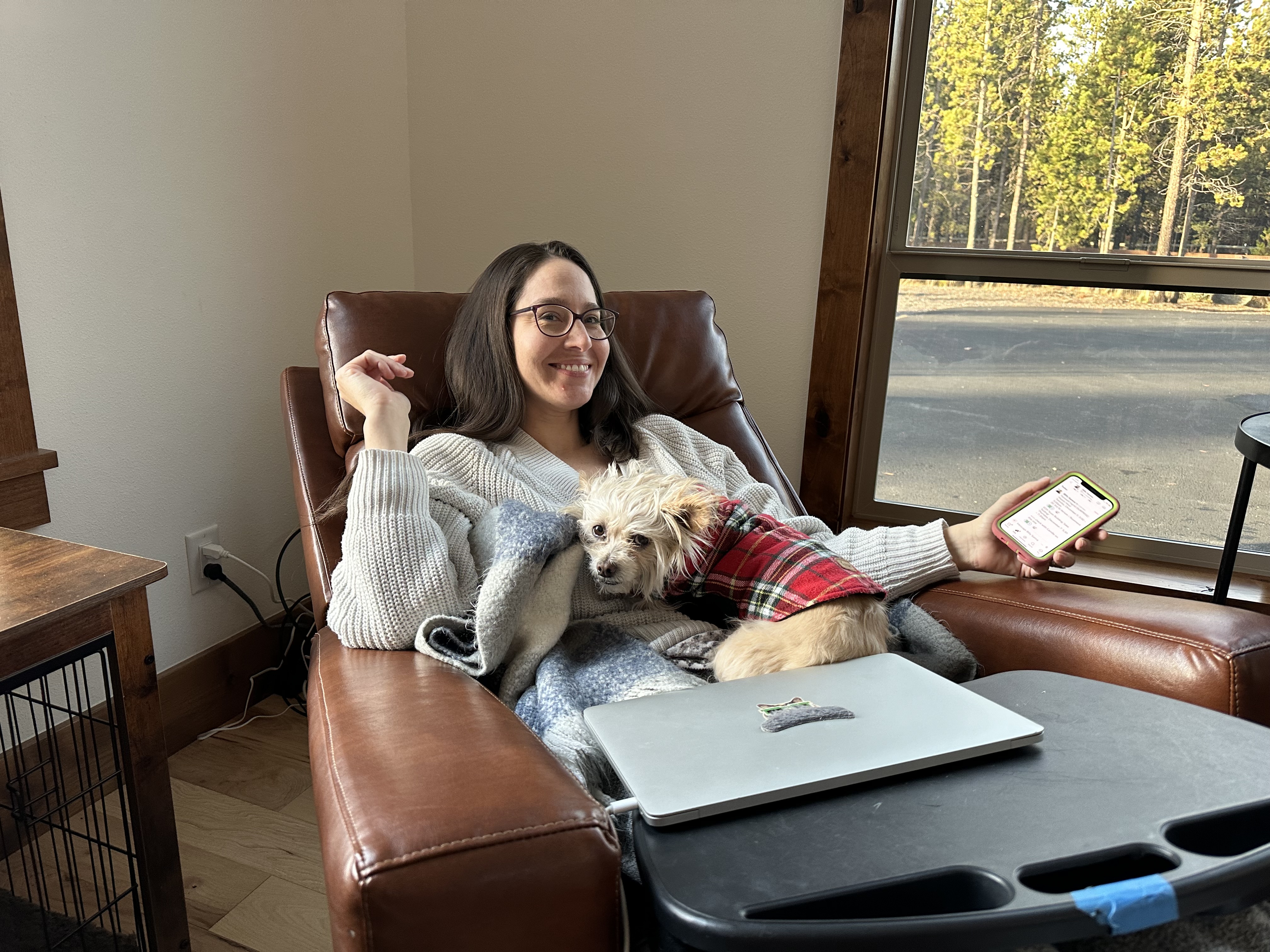 Samantha relaxing on a leather chair with a small dog and a laptop nearby