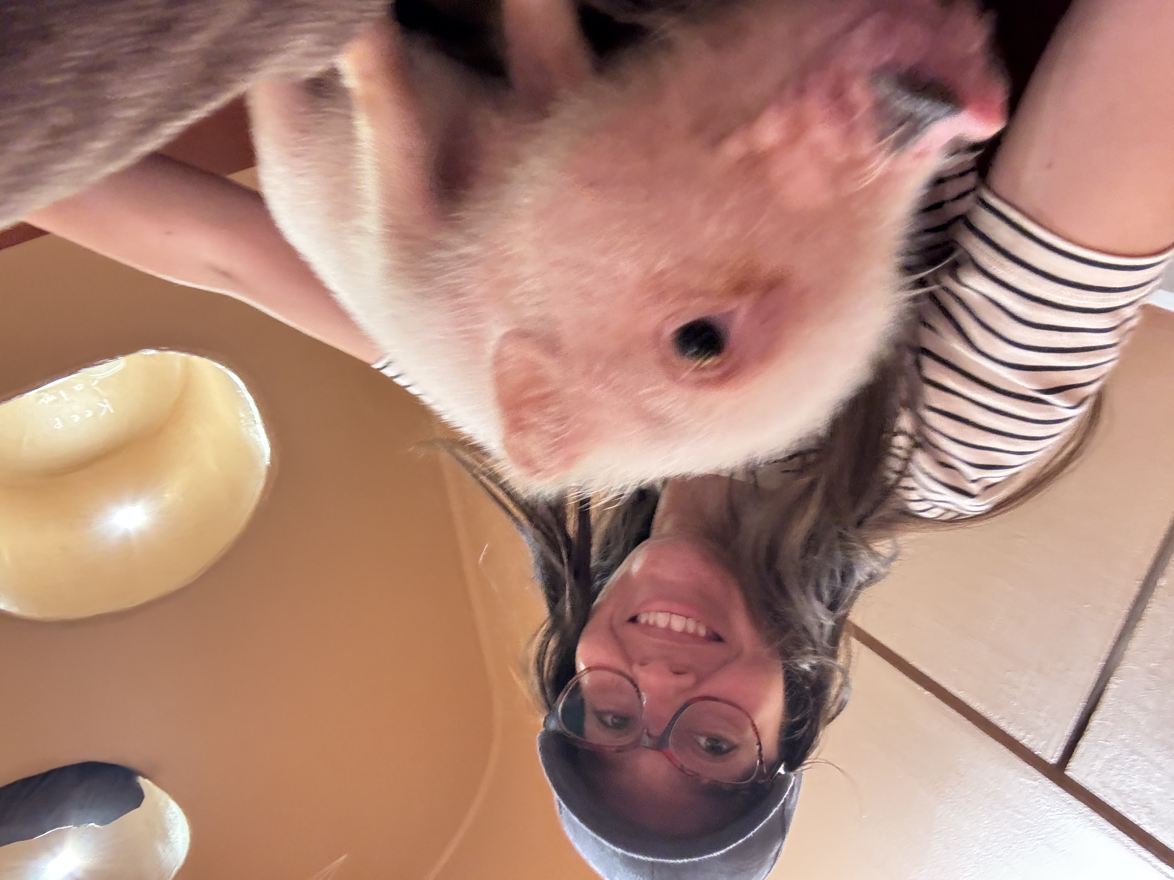 Samantha smiling with a small dog in a casual indoor selfie